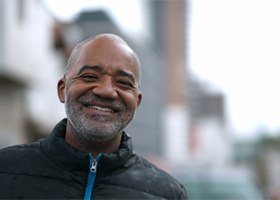 smiling older man wearing black jacket outdoors