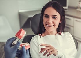 Patient in dental chair looking at smile model
