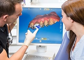 Dentist and patient looking at 3 D models of teeth on screen