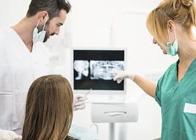 Dentist and team member looking at x rays of teeth
