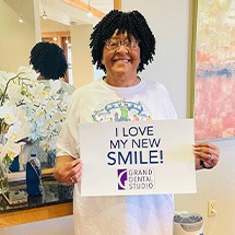 Dental patient holding sign that says I love my new smile Grand Dental Studio