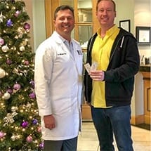 Doctor Kirk smiling with a patient in dental office with Christmas tree