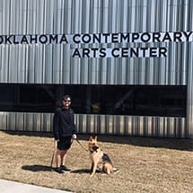 Person walking dog in front of Oklahoma Contemporary Arts Center building