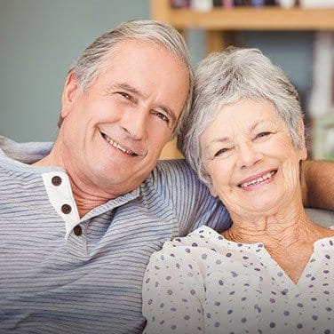 Smiling senior man and woman sitting on couch