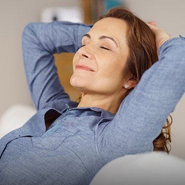 Relaxing woman laying on back with hands behind head