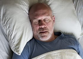 Man sleeping soundly in bed thanks to sleep apnea treatment in Oklahoma City
