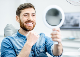 Man looking at smile in mirror after laser dentistry