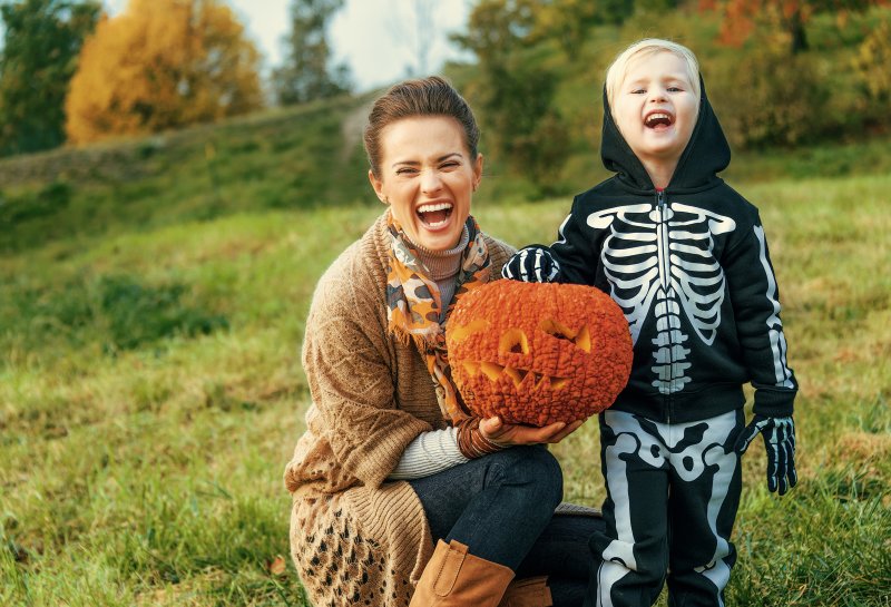 mom smiling with son and jack-o-lantern 